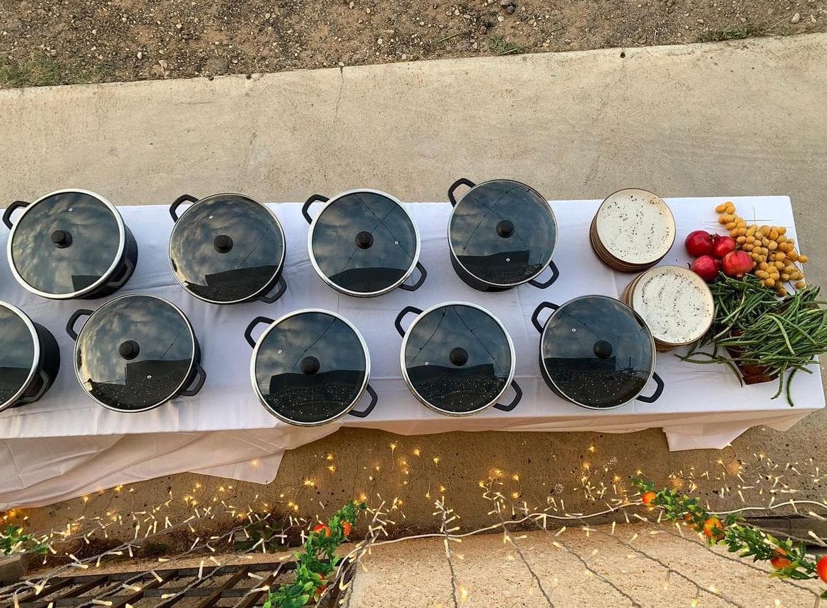 שולחן עם סירים, צלחות ופירות, מתאים להשכרת ציוד לאירועים, כולל כלי אוכל ואבזור לאירוח.